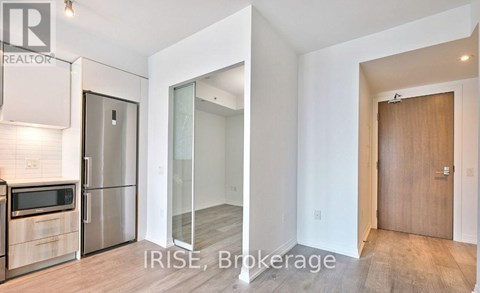 A kitchen with a refrigerator, microwave, and oven.