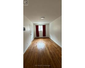A room with wooden floors and a window with red curtains.