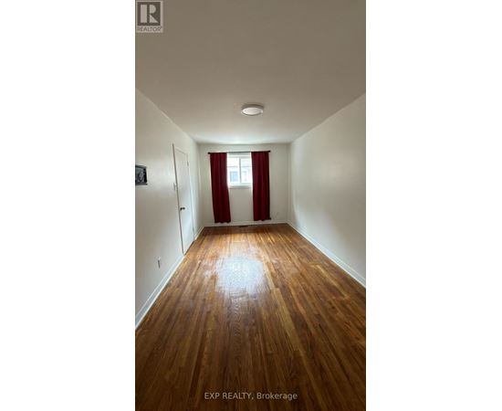 A room with wooden floors and a window with red curtains.