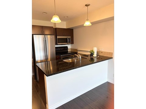 A kitchen with a black countertop and stainless steel appliances.