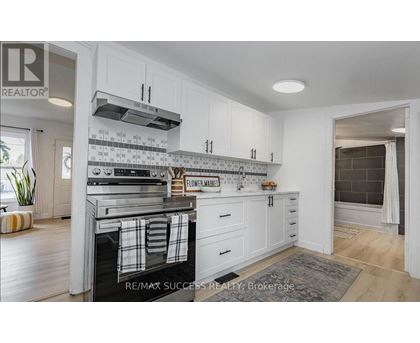 A kitchen with white cabinets and a black and white tiled backsplash.