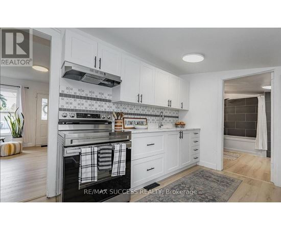 A kitchen with white cabinets and a black and white tiled backsplash.