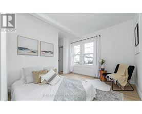 A bedroom with a bed, chair, and pictures on the wall.