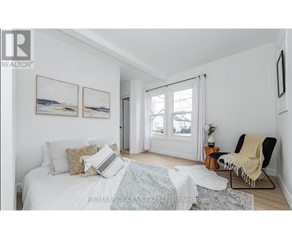 A bedroom with a bed, chair, and pictures on the wall.
