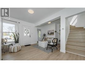 A well-lit, spacious living room with a staircase on the right.