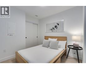 A bedroom with a bed, a nightstand, and a painting on the wall.