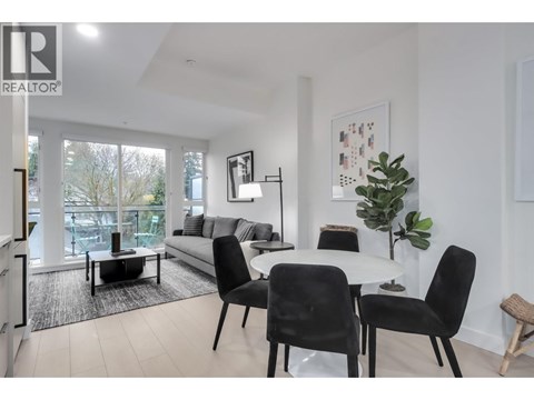 A living room with a white couch, a coffee table, and a dining table with chairs.