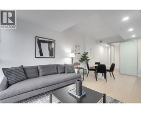 A living room with a grey couch, a coffee table, and a dining table with chairs.