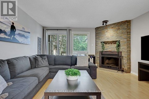 A living room with a grey couch and a fireplace.