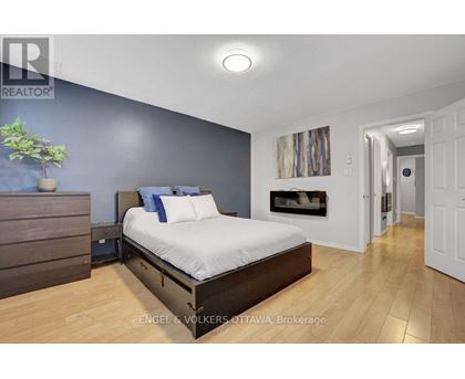A bedroom with a large bed and a plant on the nightstand.