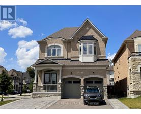 A house with a stone wall and a car parked in front.