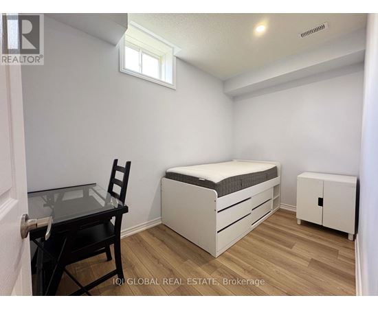 A bedroom with a bed, chair, and cabinet.