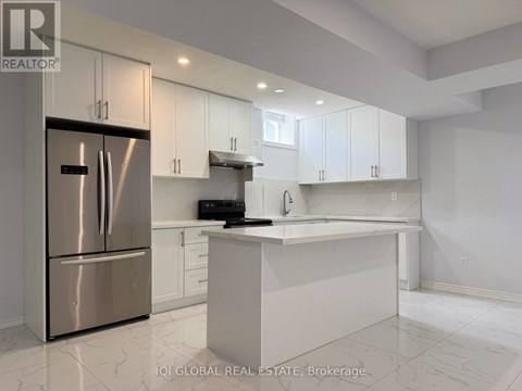 A modern kitchen with white cabinets and a stainless steel refrigerator.
