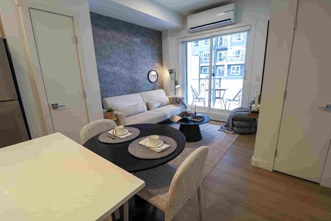 A dining room with a table set for two and a couch.