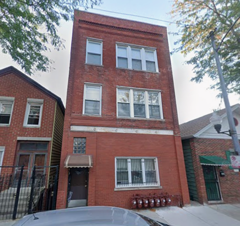 A red brick building with a black car parked in front.