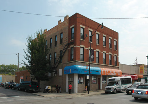 A red brick building with a blue awning sits on a street corner.