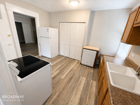 A kitchen with a white fridge, a black dishwasher, and a white sink.