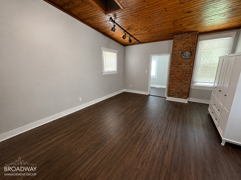 A spacious room with wooden floors and a brick pillar.