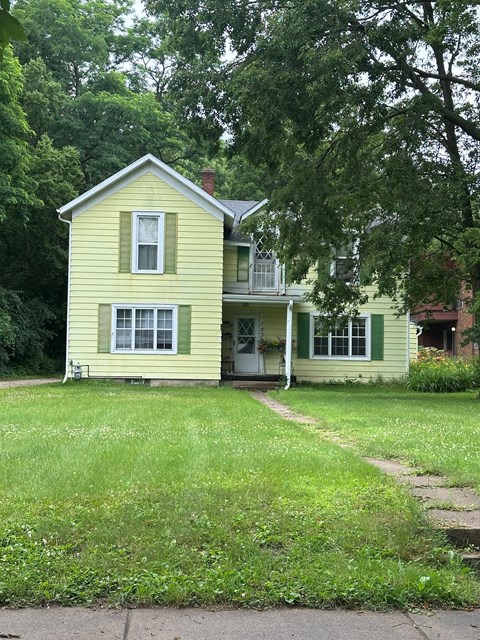A yellow house with a white door and windows.