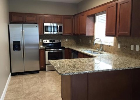 A kitchen with brown cabinets and granite countertops.