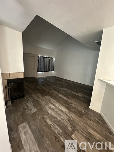 A room with wooden flooring and a fireplace.