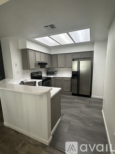 A kitchen with a white counter and a refrigerator.