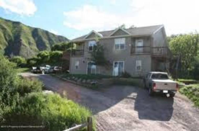 A house with a mountain in the background and a truck parked in the driveway.