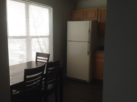 A white refrigerator is in a kitchen next to a table with two chairs.