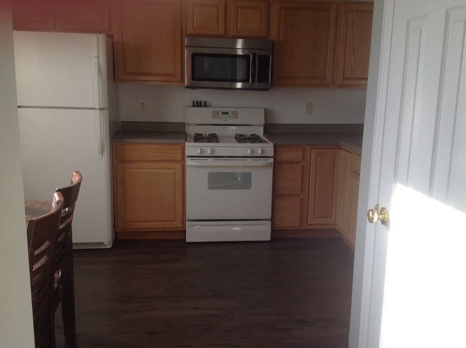 A kitchen with a white refrigerator, white stove, and wooden cabinets.