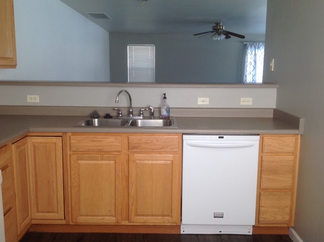 A kitchen with wooden cabinets and a white dishwasher.