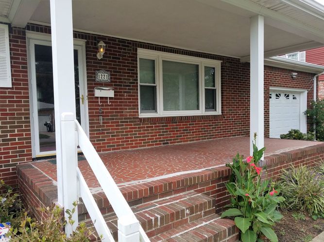A red brick house with a white door and windows.