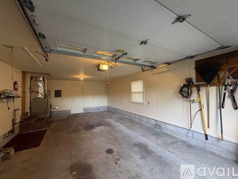 A spacious garage with a red rug on the floor and various tools hanging on the wall.