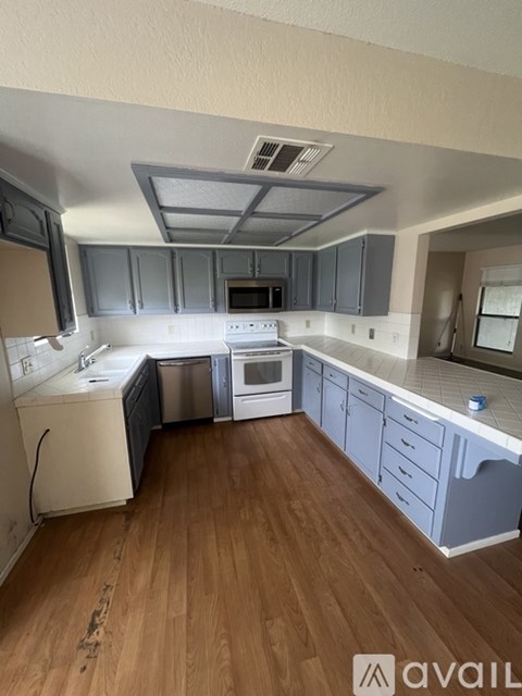 A kitchen with wooden floors and a white dishwasher.