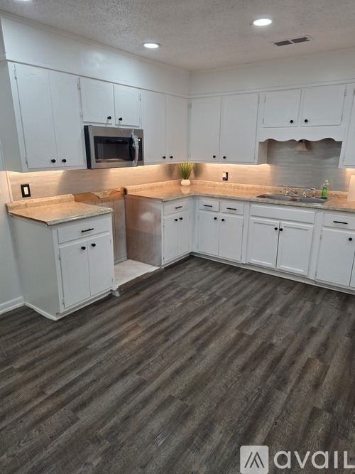 A kitchen with white cabinets and a wooden floor.
