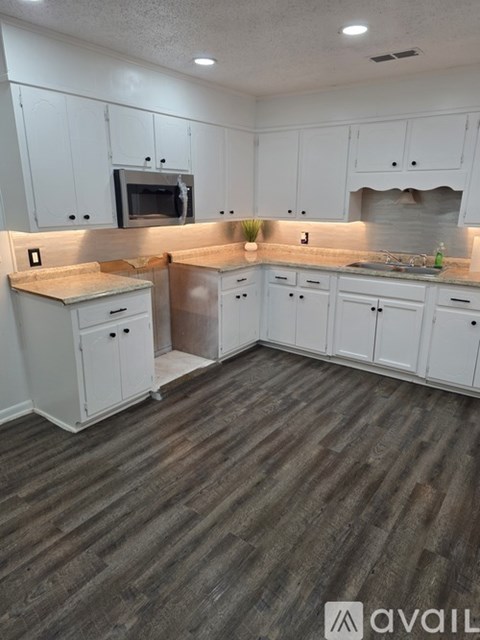 A kitchen with white cabinets and a wooden floor.