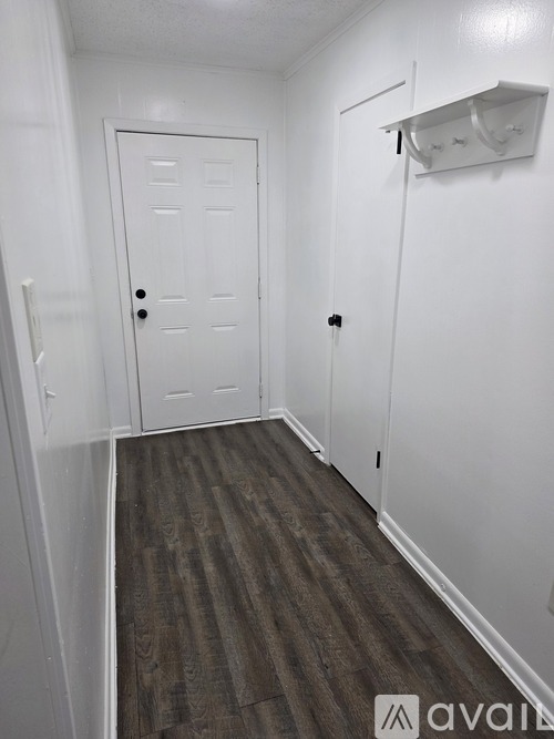 A hallway with a white door and a white wall.