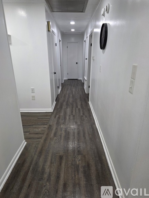 A long hallway with wood flooring and white walls.
