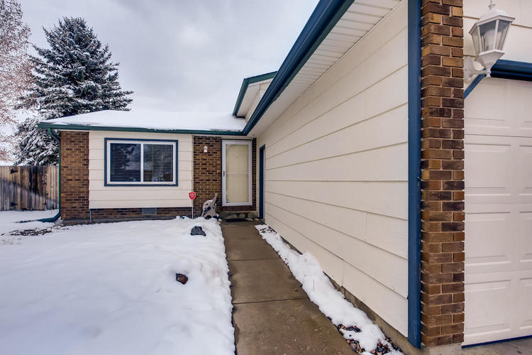 A house with a snow-covered ground and a tree in the background.