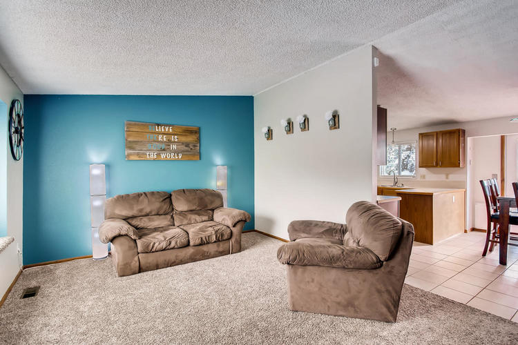 A living room with a couch, chair, and a clock on the wall.
