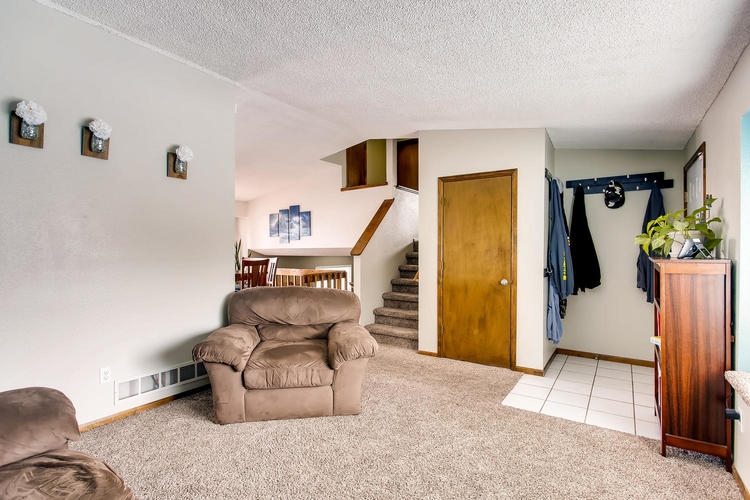 A living room with a brown recliner and a staircase.
