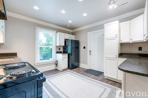 A kitchen with a black fridge and white cabinets.