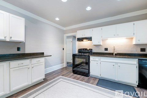 A kitchen with white cabinets and a black countertop.