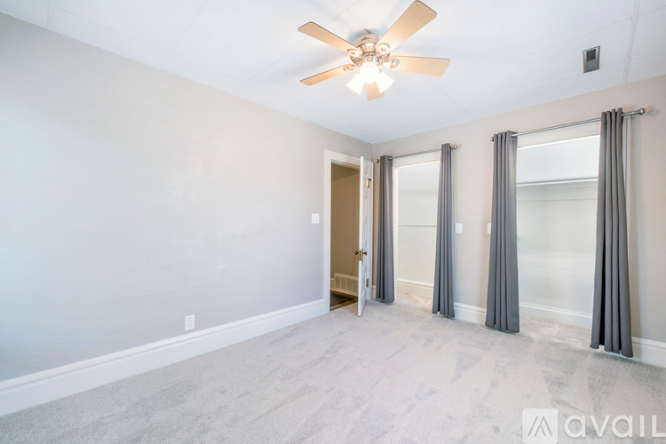 A spacious room with a ceiling fan and a door leading to another room.