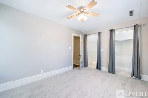 A spacious room with a ceiling fan and a door leading to another room.