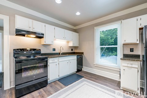 A kitchen with white cabinets and a black oven.