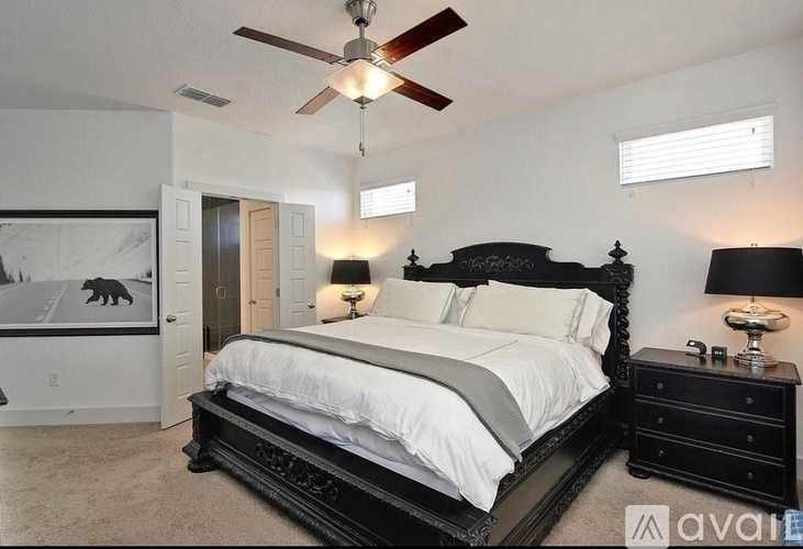 A bedroom with a large bed and a ceiling fan.