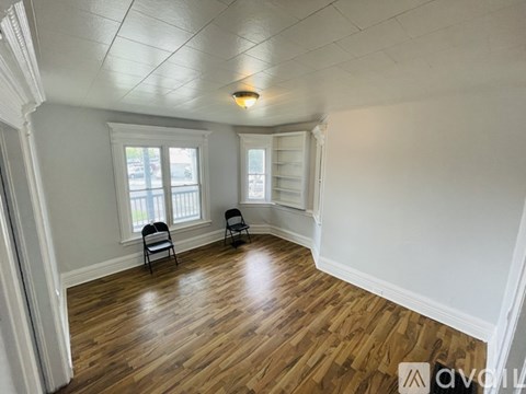 A room with wooden floors and two chairs.