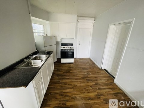 A kitchen with white cabinets and a wooden floor.