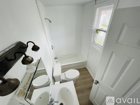 A bathroom with a toilet, sink, and window.