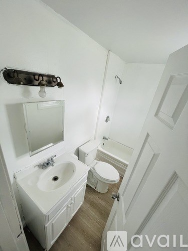 A white bathroom with a toilet, sink and mirror.